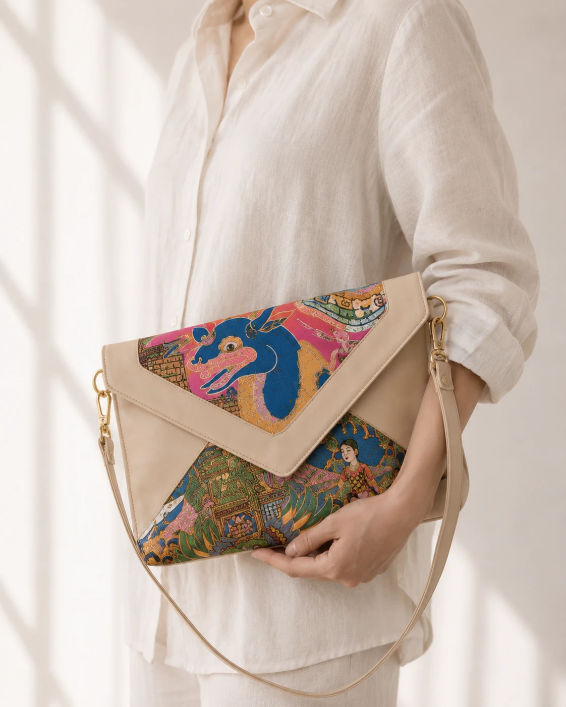 Natural envelope crossbody with pink and blue Pugur painting panels, held against white linen